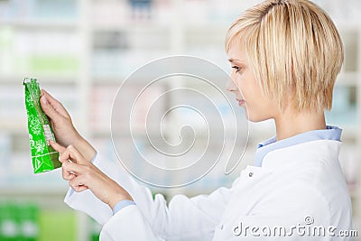 Female Pharmacist Reading Product Details In Pharmacy