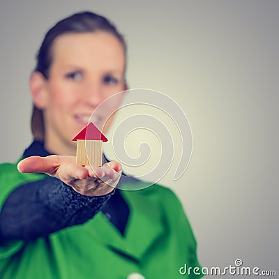 Female real estate agent holding out a model house