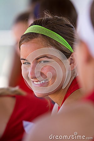 Female softball player smiles in dugout