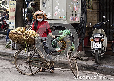 Female street vendor selling pineapples out of a basket on her b