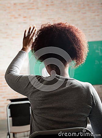 Female Student Raising Hand To Answer In Classroom