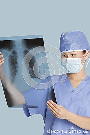 Female surgeon analyzing x-ray report over light blue background