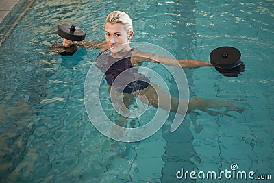 Female swimmer working out with foam dumbbells in swimming pool