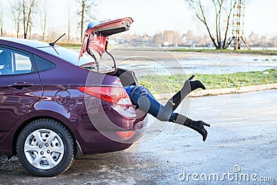 Female swinging her legs into car luggage trunk