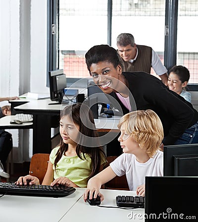 Female Teacher With Students At Desk