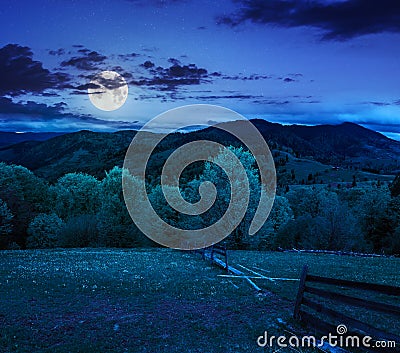 Fence on hillside meadow in mountain at night