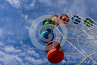 Ferris wheel against blue sky with white clouds