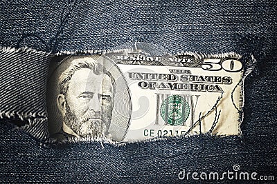 Fifty dollars bill through torn blue jeans texture