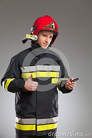 Firefighter holding cell phone and showing thumb up.