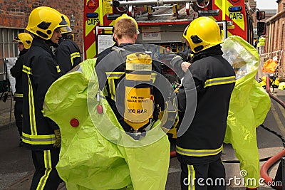 Firefighters in breathing apparatus don protective suits.