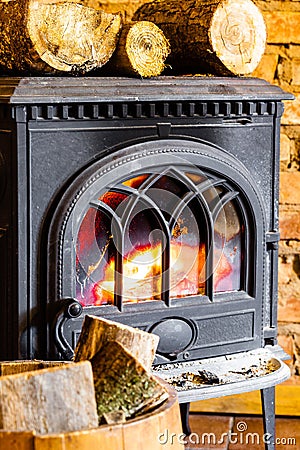 Fireplace with fire flame and firewood in barrel interior. Heating.