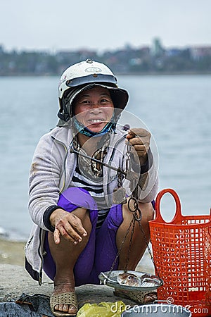 Fish selling woman with simple scale at market.