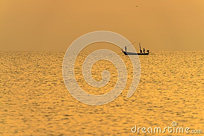 Fisherman on the boat over dramatic sunset