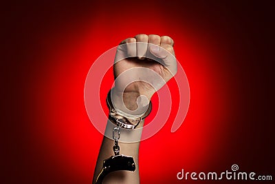 Fist and handcuffs opened over red background