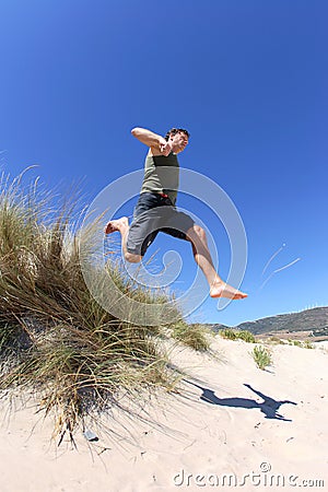 Fit, healthy middle aged man leaping over sand dunes