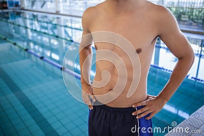 Fit man in swimming trunks standing by the pool