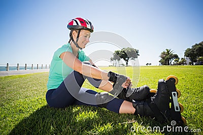 Fit mature woman tying her roller blades on the grass