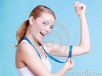 Fitness girl sporty woman measuring her biseps on blue