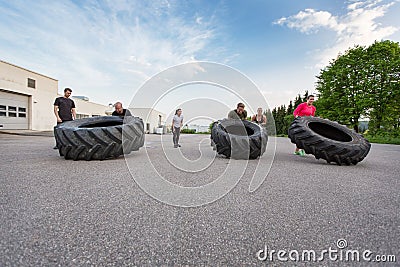 Fitness team flipping heavy tires outdoor
