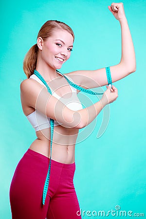 Fitness woman with measure tape measuring biceps
