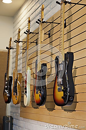 Five electric guitars hanging on display rack in store for sale