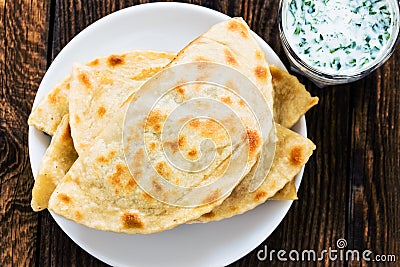 Flat bread on a plate with glass of sour milk viewed from above