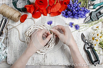 Florist at work. Woman decorating wicker wreath with wild flower