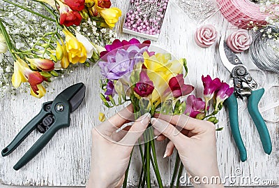 Florist at work. Woman making bouquet of freesia flowers