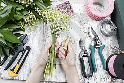 Florist at work. Woman making bouquet of lily of the valley flow