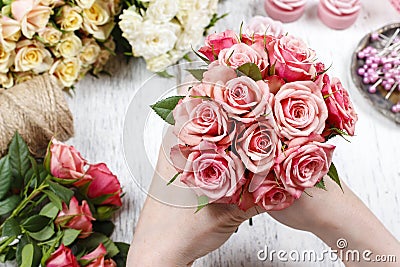 Florist at work. Woman making bouquet of pink roses