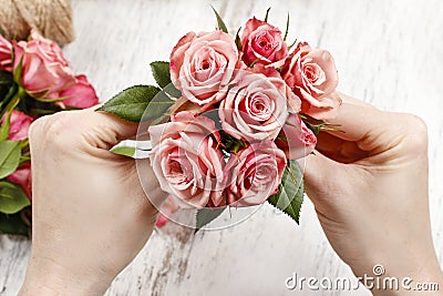 Florist at work. Woman making bouquet of pink roses