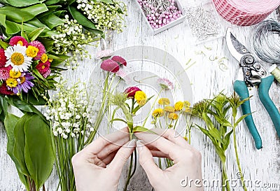 Florist at work. Woman making bouquet of wild flowers