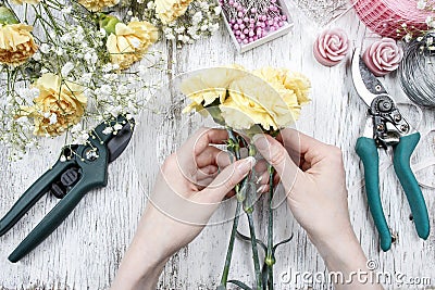 Florist at work. Woman making bouquet of yellow carnations