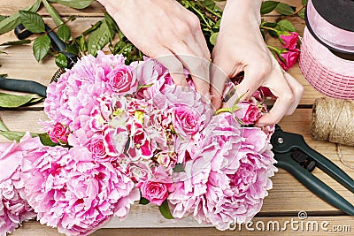 Florist at work: woman making floral decoration of pink peonies