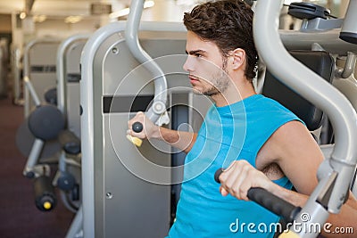 Focused man using weights machine for arms