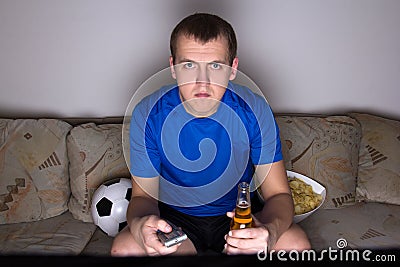 Football supporter in uniform watching tv