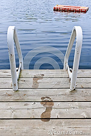 Footprints on dock at summer lake