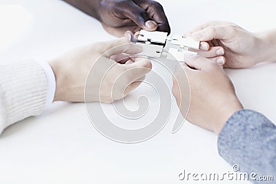 Four business people holding jigsaw puzzle pieces and placing them together, hands only