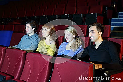 Four people watch movie in movie theater.