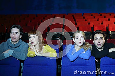 Four young scared and surprised people watch movie