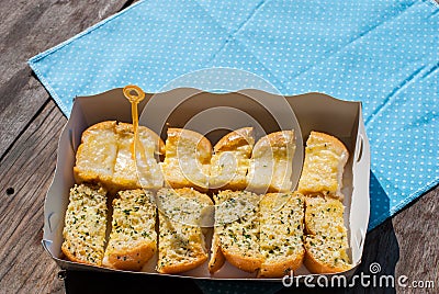 Fresh-baked garlic bread with herbs, on white bread tray