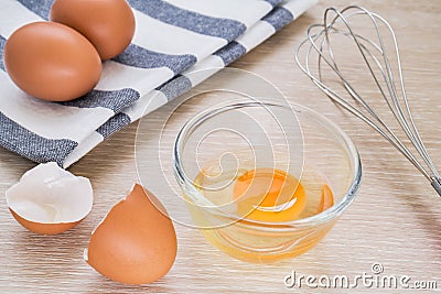 Fresh egg in bowl and metal whisk