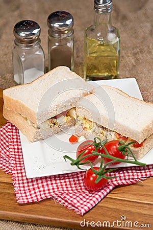 Fresh egg and tomato on white sandwich in rustic kitchen setting