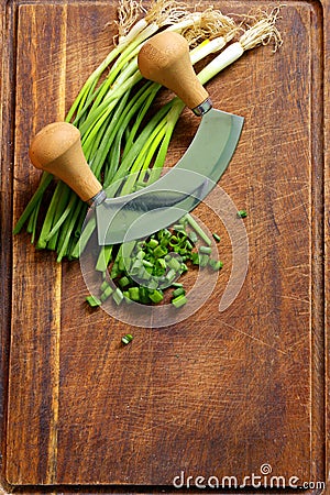 Fresh green chives on wooden board with knife