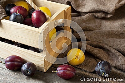 Fresh plums in box on wooden board