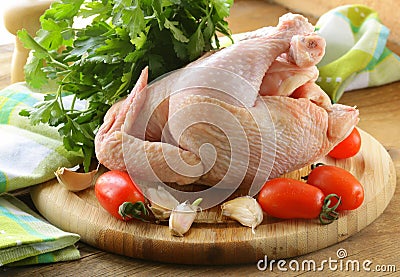 Fresh raw chicken on a cutting board with vegetables