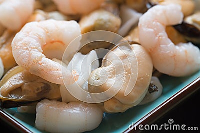 Fresh raw seafood mix of prawns mussels and squid on serving pla