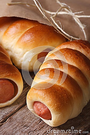 Fresh rolls with sausage closeup unpacked paper vertical