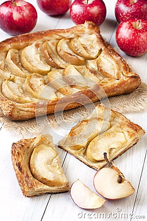 Fresh slice of apple pie with whole pie on wooden background