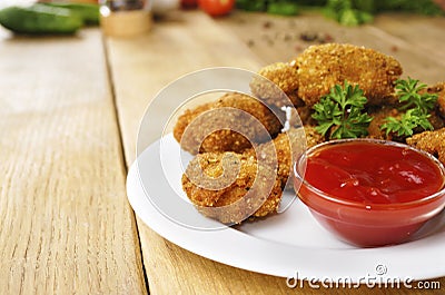 Fried chicken nuggets on the plate on the wooden table